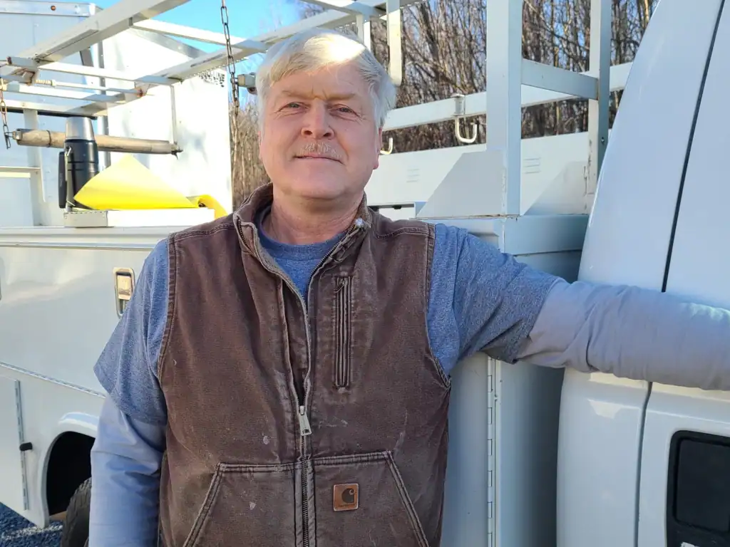 Experienced electrician leaning on his truck.