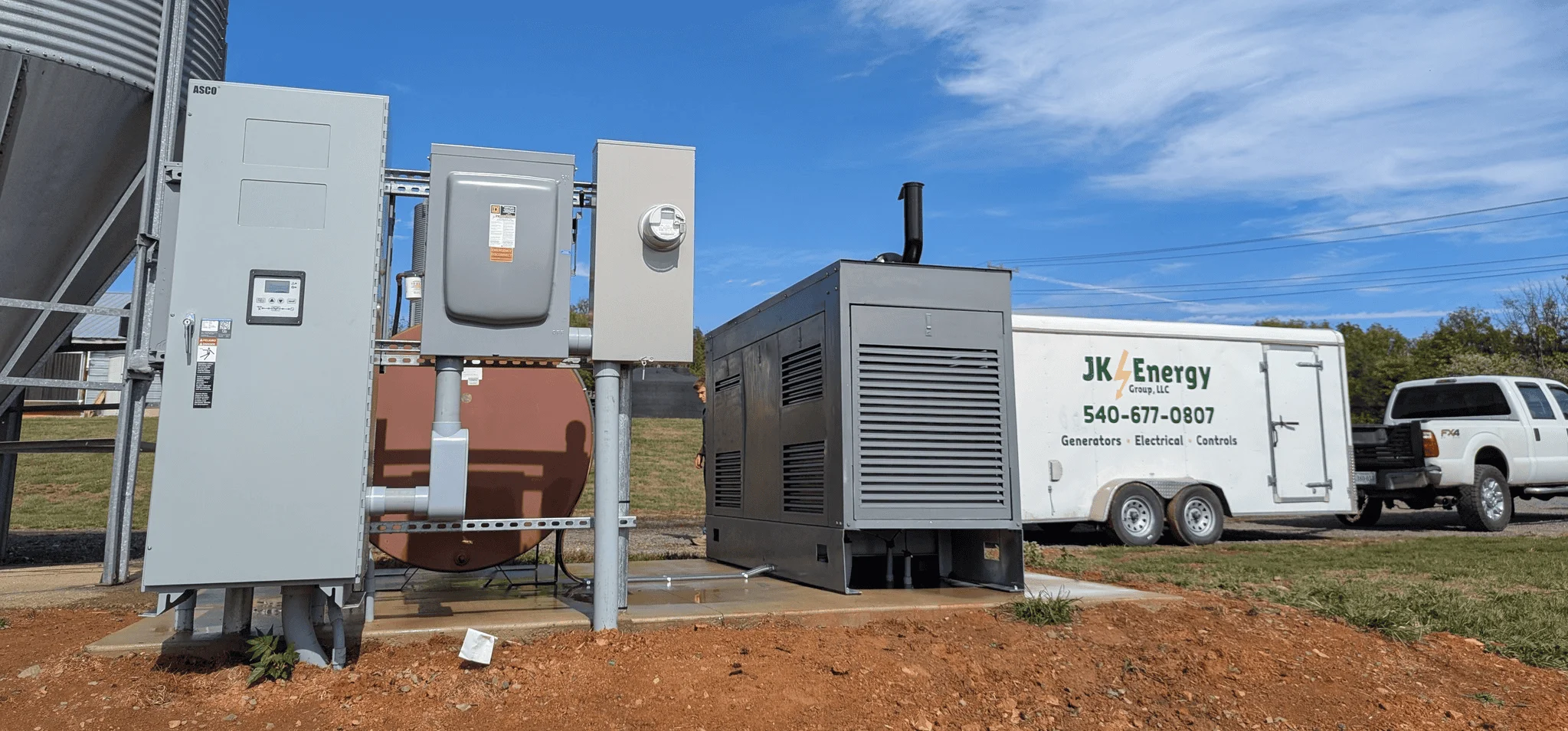 An agricultural electrical setup with generators, controls, and testing equipment and a JK Energy service trailer